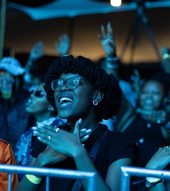 A smiling festival-goer in glasses clapping at the barrier